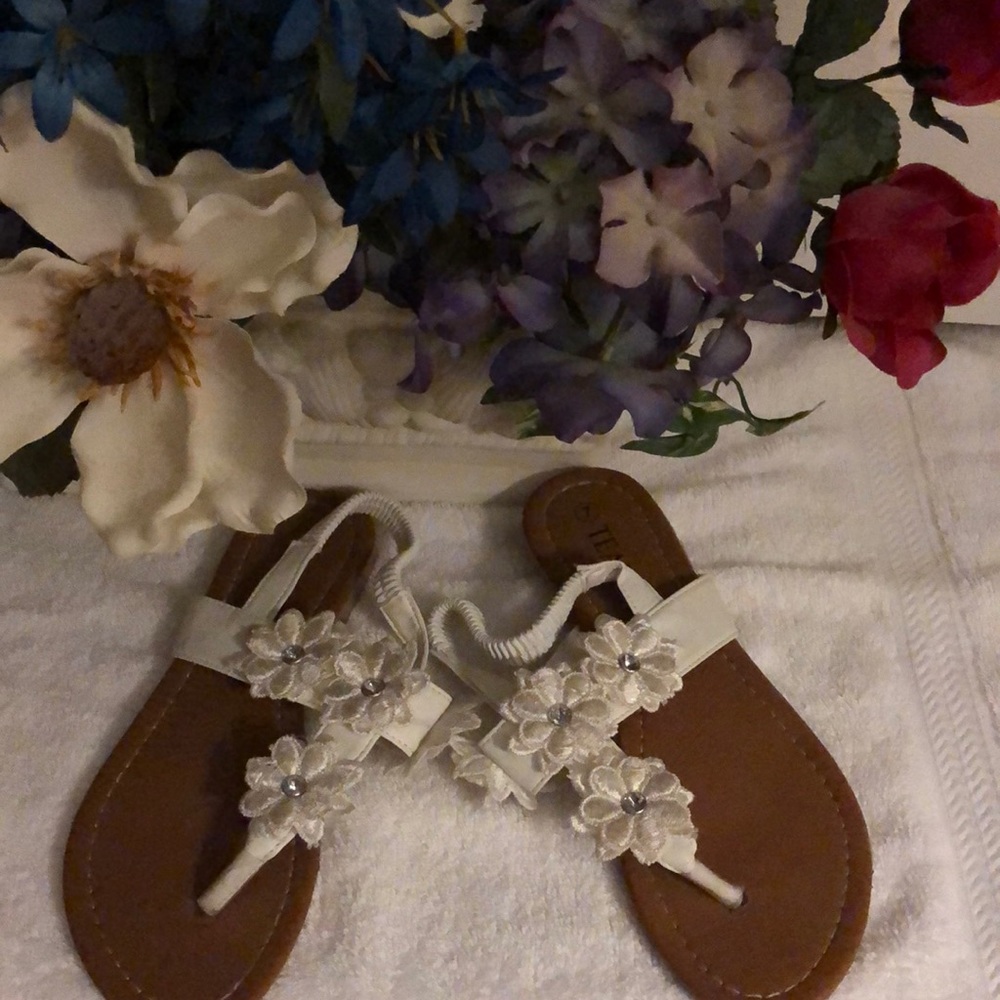 A pair of size 7 TEAM white floral thong sandals